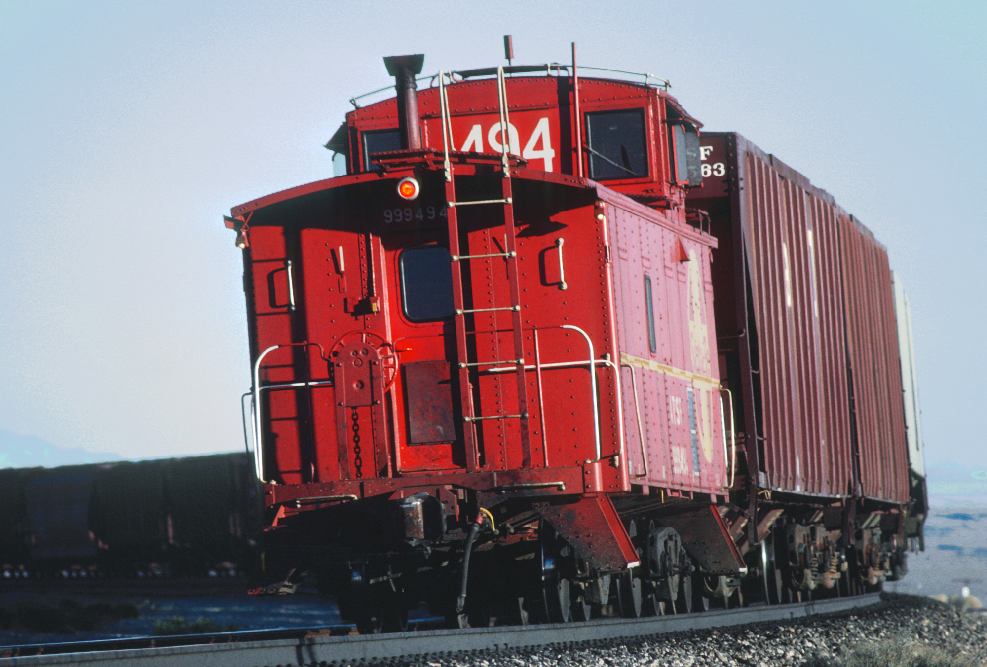 A classic Santa Fe caboose tags along at the tail end of a freight train in...