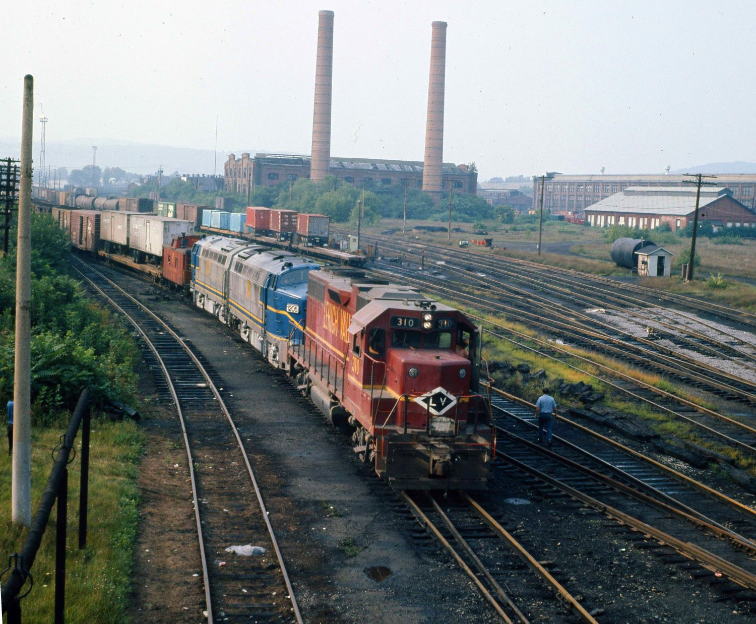 Lehigh Valley GP38AC 310 brings Delaware and Hudson RF-16s and their train into Sayre Pennsylvania in August 1975